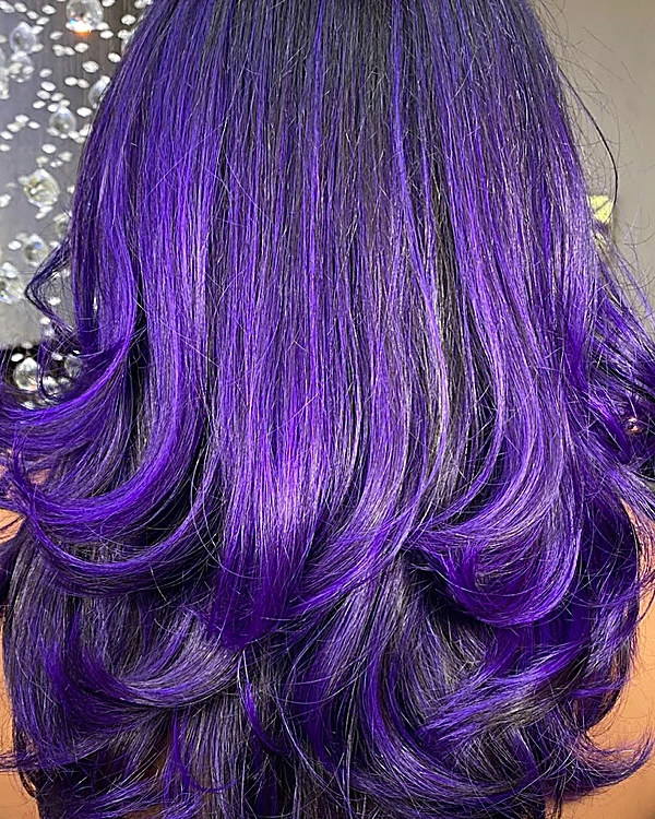Cabello en capas teñido de violeta eléctrico sobre base oscura, visto de espaldas