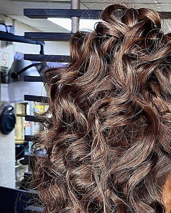 Peinado de gala: media cola con rizos castaños voluminosos, visto por detrás