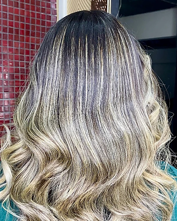 Rubio ceniza con raíz oscura y ondas, frente al mosaico rojo y el espejo dorado del salón