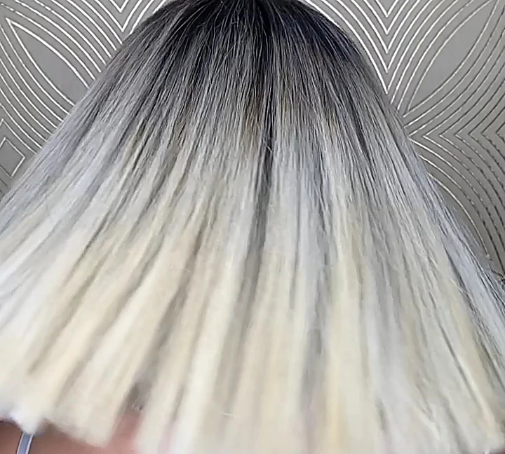 Rubio platino con raíz oscura en movimiento frente al papel tapiz de líneas doradas